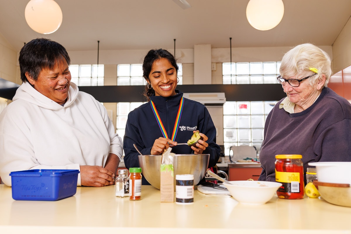 A group of three smiling while cooking.