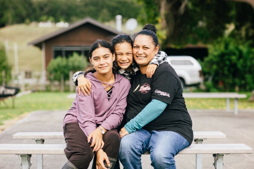 Family of three hugging for a photo.